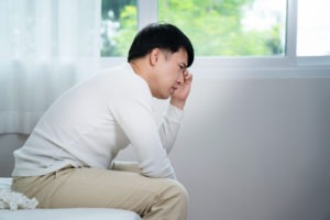 sad Asian man sitting on a bed