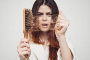 woman pulling hair out of a hairbrush